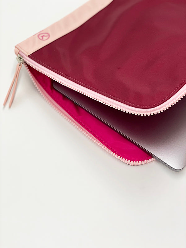 A chic fully padded laptop sleeve made by water-resistant nylon and faux leather in the color of plum and pink.