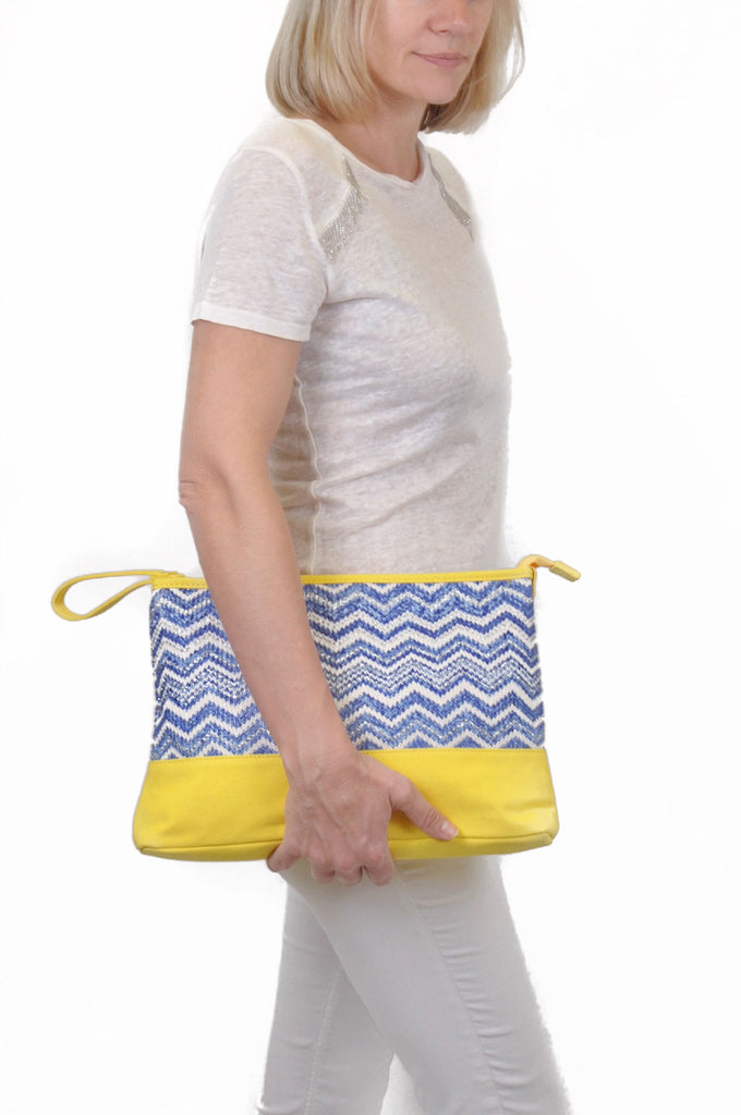 model wearing a cosmetic travel pouch in blue and yellow patterns