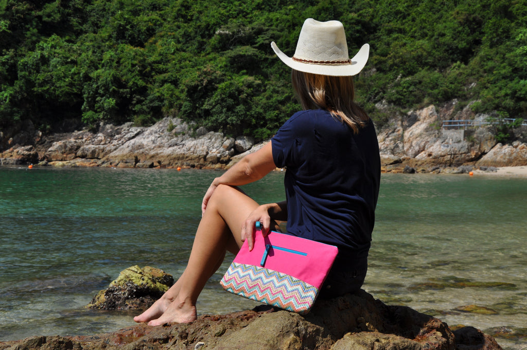 Woman at the beach with a pink MAKARON beach pouch on her side