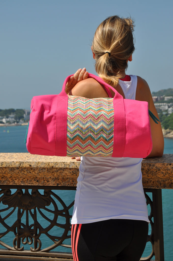 woman watching the sea with a pink nylon gym bag