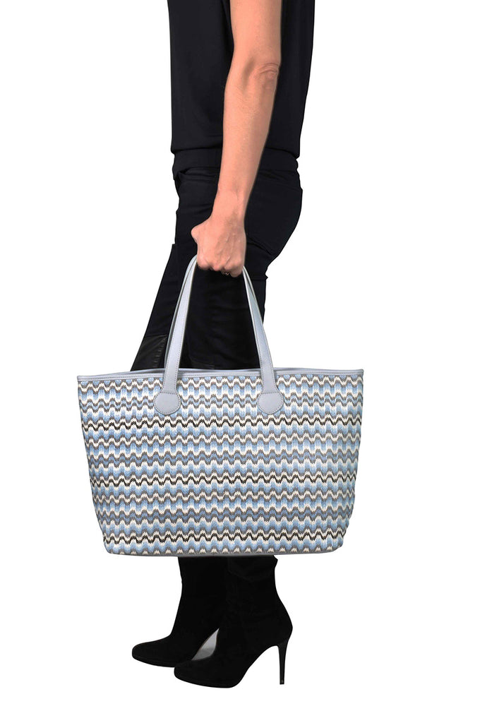 woman wearing a grey and blue zigzag shoulder tote bag