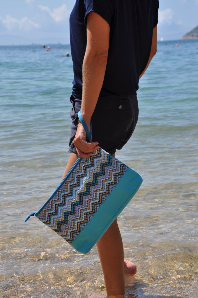 woman at the beach carrying a blue cosmetic travel bag